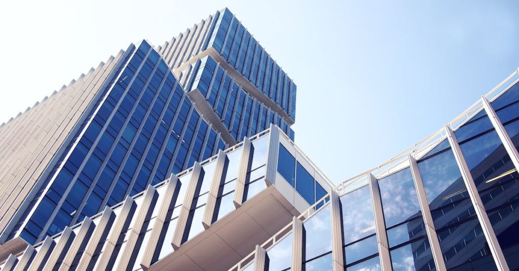 Low-angle shot of a modern skyscraper with reflective glass design under a clear blue sky.